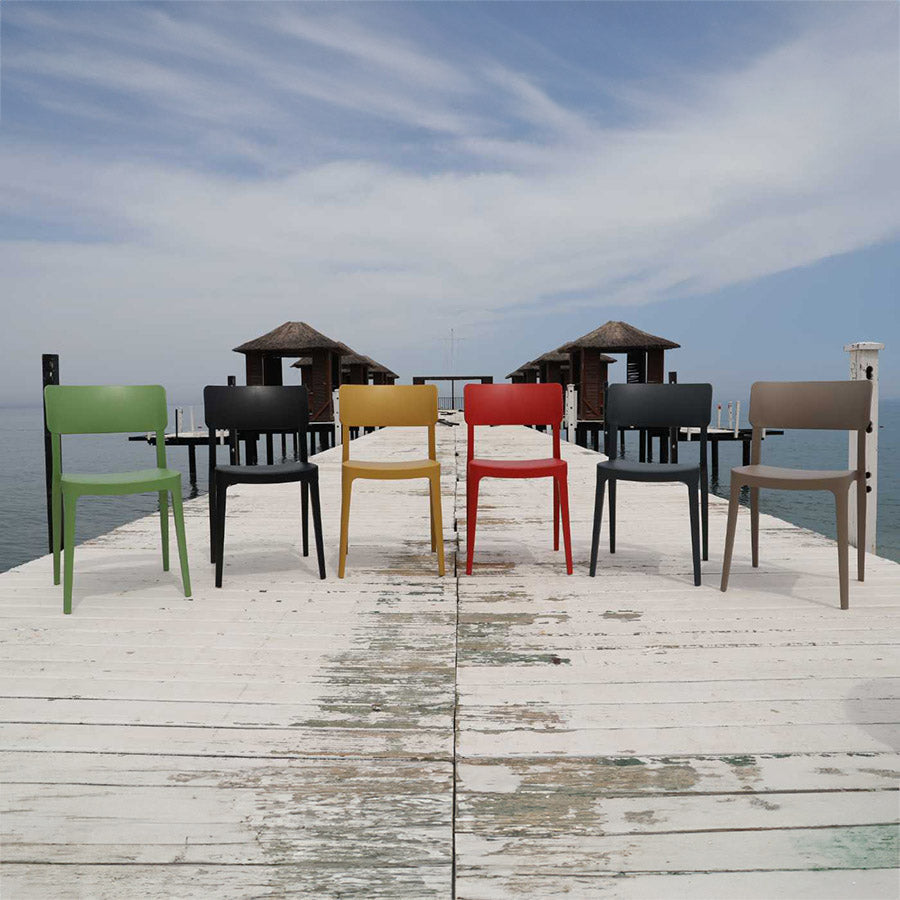 Colorful chairs on a wooden pier with a blue sky and water background